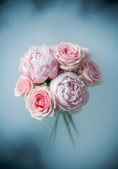 Fototapeta premium Bouquet of pink flowers is floating in the air, surrounded by a blue mist. The flowers are delicate and beautiful, with a sense of ethereal grace. The blue mist adds a dreamy