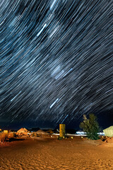 Star trails over desert camp, night sky.