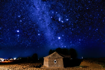 Desert hut under a brilliant starry night sky.
