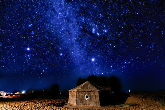 Desert hut under a brilliant starry night sky.