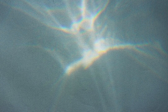 Blurred water texture overlay effect for photo and mockups. Organic drop diagonal shadow and light caustic effect on a white wall. Shadows for natural light effects