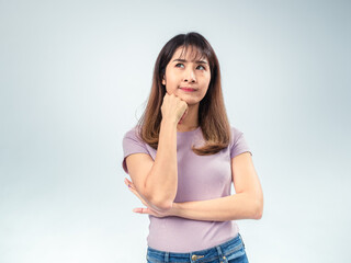 Asian woman in purple t-shirt and jeans looking to the side with thoughtful expression, hand...