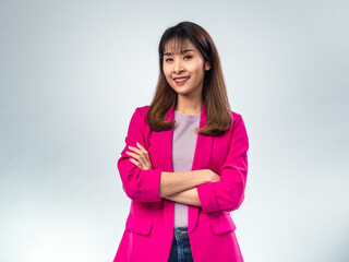 Asian woman in bright pink blazer and purple t-shirt crossing arms with confident expression,...