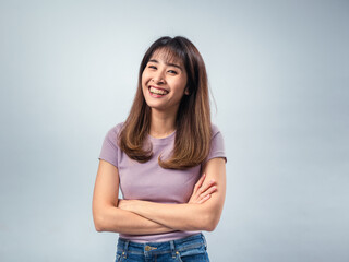 Asian woman standing with arms crossed, wearing a purple t-shirt and jeans, showing a serious and...
