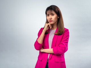 Asian woman in pink blazer and purple t-shirt standing with hand on chin, looking up with serious...