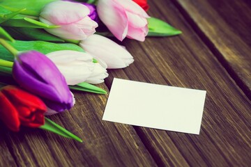 Flat design is showing multicolored tulip cluster on wooden slatted table with blank white card