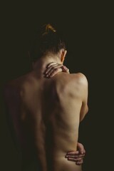 Single woman is placing hand on neck and highlighting spine in flat design with dark backdrop