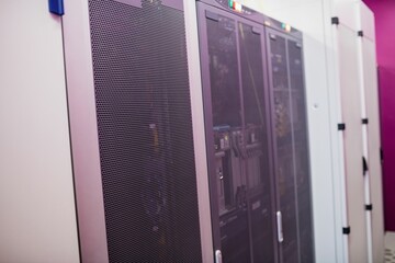 Server cabinets are standing in flat design data center, showing mesh doors, LED lights, cables