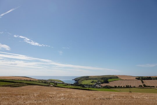 Fototapeta Coastal farmland is showing rolling fields in flat design, featuring stone walls and sea inlet