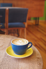 Coffee cup with latte art in cozy cafe interior