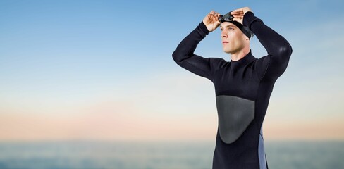 Male swimmer looking away while standing on shore