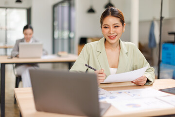 Shot of a asian business female working on laptop computer in her workstation.Portrait of Business...