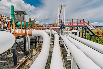 Male worker inspection at steel long pipes and pipe elbow in station oil factory during refinery valve of visual check record pipeline tank oil