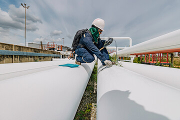 Male worker inspection and measurement thickness pipeline oil and gas at check record