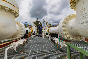Male worker inspection at steel long pipes and pipe elbow in station oil factory during refinery...