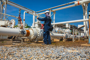 Production operator opening ball valve at pipeline oil and gas wellhead remote platform to control...