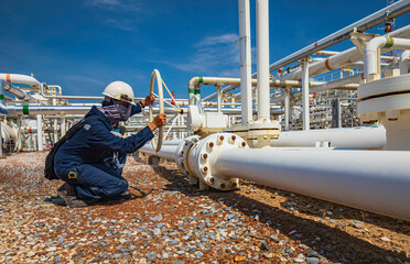 Production operator opening ball valve at pipeline oil and gas wellhead remote platform to control...