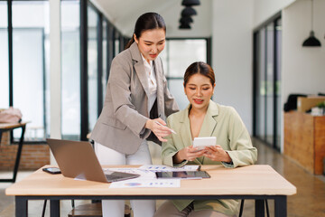 Team of business partnership use calculator to calculate coworkers analysis strategy with discussing a financial planning graph and company budget during a budget meeting in office.
