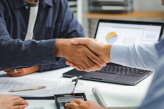 Professional business handshake during financial consultation with advisor, partnership agreement at meeting table with charts and documents - Powered by Adobe