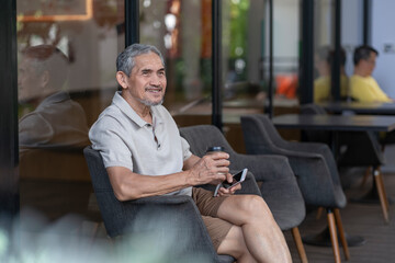 smiling senior man holding coffee cup and smartphone resting at coffee shop,elderly...
