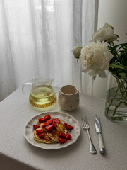 A cozy morning and breakfast by the window - chamomile tea, pancakes with fresh strawberries and...