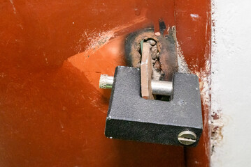 orange old iron door to house with black padlock