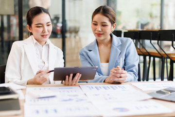 Portrait of Two casual asian business women at work.doing planning analyzing the financial report,...
