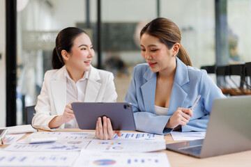 Portrait of Two casual asian business women at work.doing planning analyzing the financial report,...