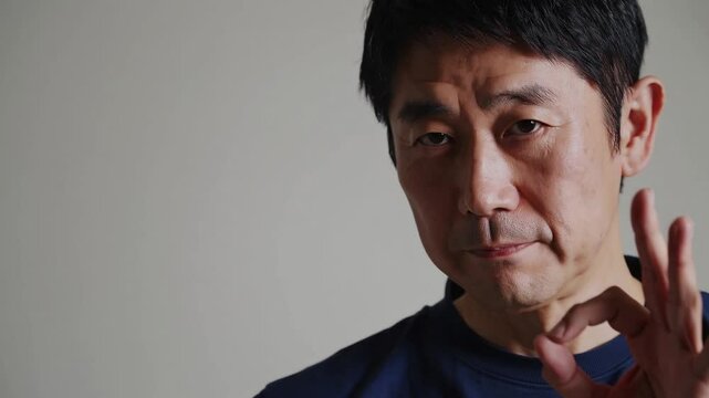 Confident Japanese Man Gesturing OK with Thumb and Index Finger