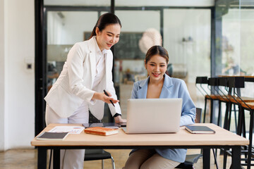 Two Young Asian Happy business women discuss new startup project Idea presentation, analyze planning and financial statistics and investment market at office.
