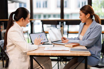 Team of confident business people point to graphs and charts to analyze market data, balance sheet, account, net profit to plan new sales strategies to increase production capacity.	