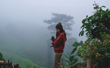 A woman holding and playing with a cat with a beautiful nature view on foggy morning