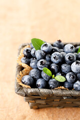 Ripe blueberries in wicker basket on wooden table.