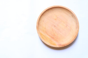 Top view of an empty round wooden plate on a white background