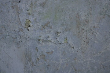 Close-up of an old, weathered wall with peeling paint, cracks, and rough texture. The surface shows...