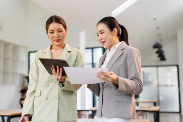 Two asian business finance market analyst in standing working at office .Business women analyze...