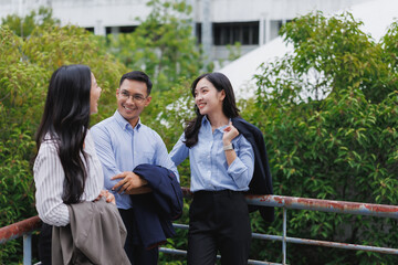 Asian business people talking and smiling outdoors on a balcony
