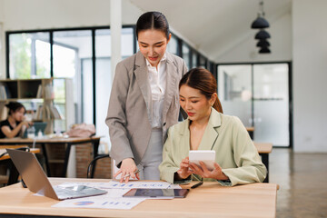 Two asian business finance market analyst in standing working at office .Business women analyze document Graphs and diagramm on tablet laptop screen.
