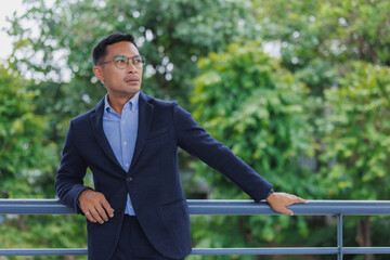 Pensive businessman leaning on railing and looking away outdoors