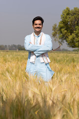 Portrait of confident mid adult male farmer with scarf standing at agricultural field.