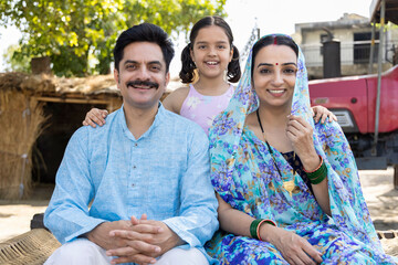 Obraz premium Happy rural family sitting on traditional bed at village