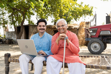 Father and son using laptop at village.