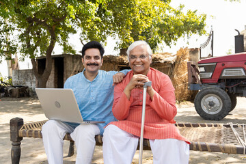 Father and son using laptop at village.