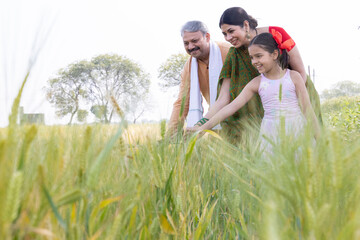 Happy parents with children having fun on agricultural field.