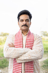 Portrait of confident mid adult male farmer with scarf standing at agricultural field.