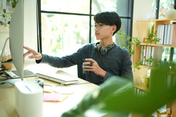 Asia teenage man using laptop for distance education and doing homework online.  Young man gamer playing broadcast game on the computer for relax and rest time.