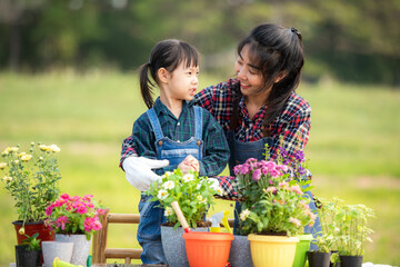 Asian  kid daughter helping mother water and sapling  the plant tree outdoors in nature spring for reduce global warming growth feature and take care nature earth.  Environment Concept