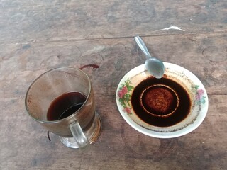 Half Empty Coffee Cup and Plate with Grounds on Wooden Table