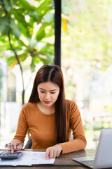 Woman sitting at laptop computer, making notes, calculating expenses, planning family budget, debts...