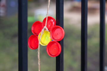 colorful flower ornaments made of recycled plastic bottles decorating a nursery school fence